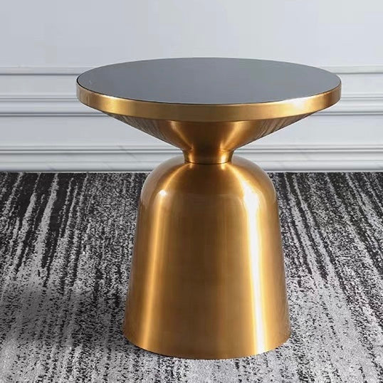 Close-up view of the gold base and black glass top of the side table.