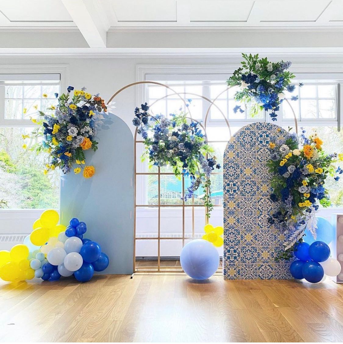 Round Top Backdrop adorned with blue and yellow flowers and balloons in a bright event space.