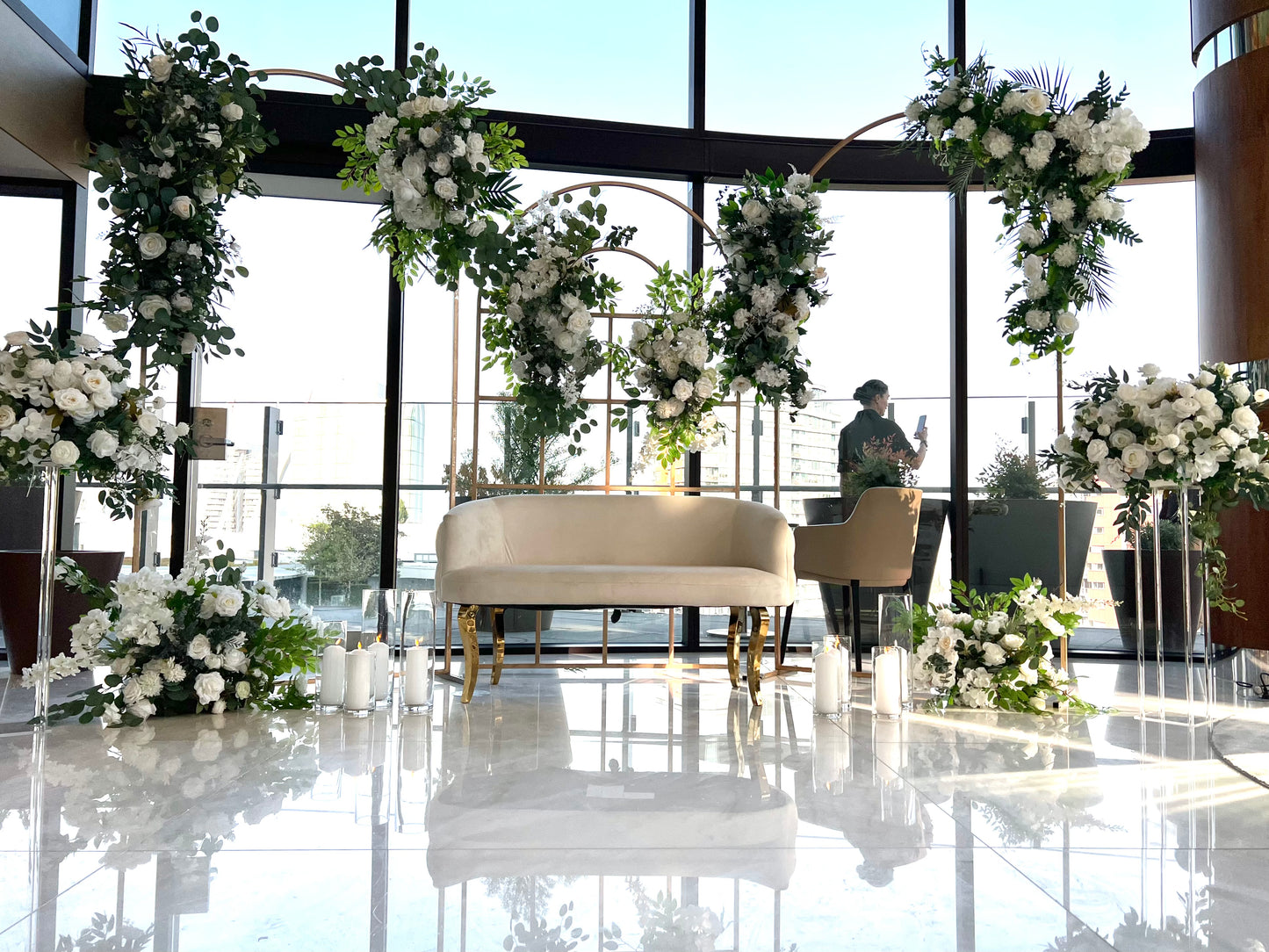 Elegant gold metal round top arch decorated with flowers for a wedding ceremony.
