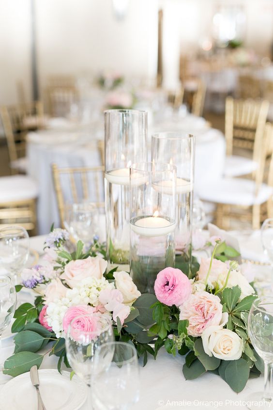 Table centerpiece with floating candles in glass vases.