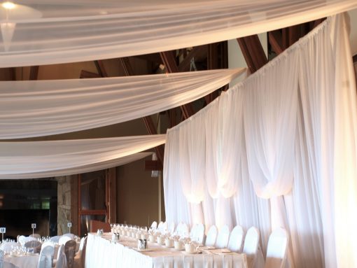 White draping with lights, enhancing the decor of an event hall.