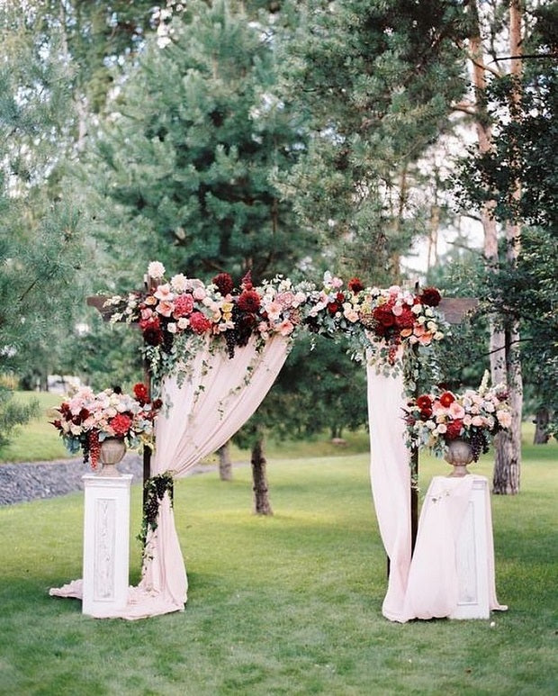 Wooden arbor arch decorated with flowers and fabrics for a wedding ceremony.