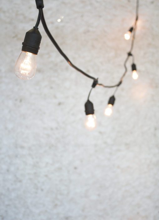 Close-up of hanging globe string lights against a wall.