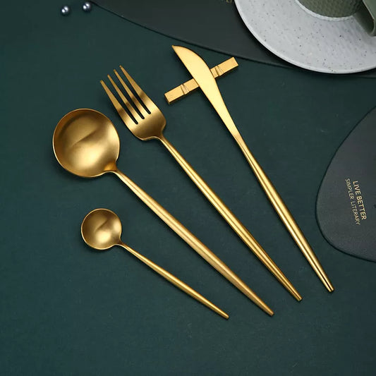 Elegant gold cutlery set including dinner knife, fork, spoon, and teaspoon on a dark green background.