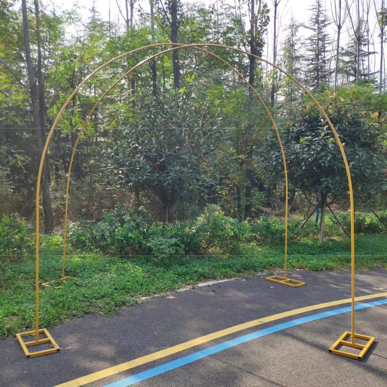 Golden semicircle double arch set on the ground at an outdoor venue