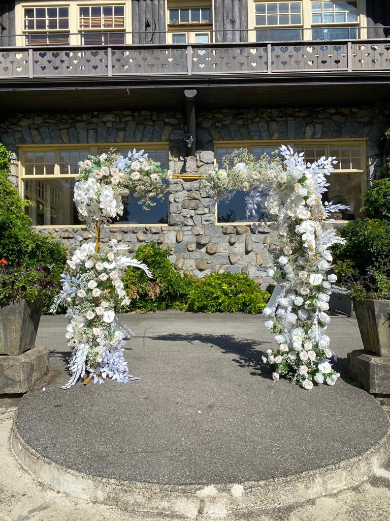 Gold rectangle arch decorated with flowers for an outdoor wedding ceremony.