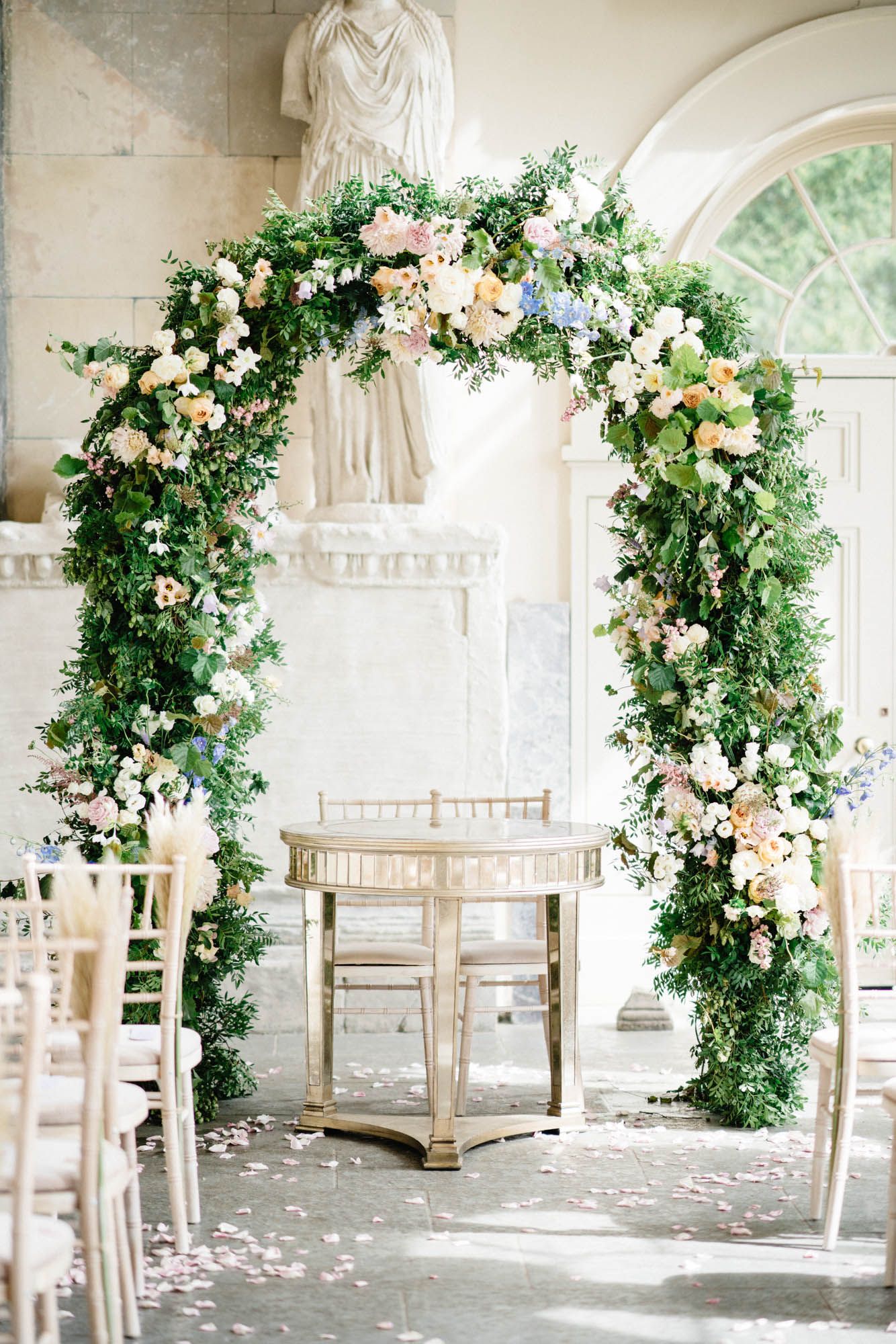 Elegant white metal arch used as a backdrop for an outdoor garden event.