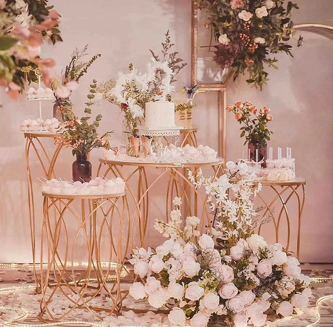 Set of 5 Gold Stands elegantly displaying desserts and flowers at an event.