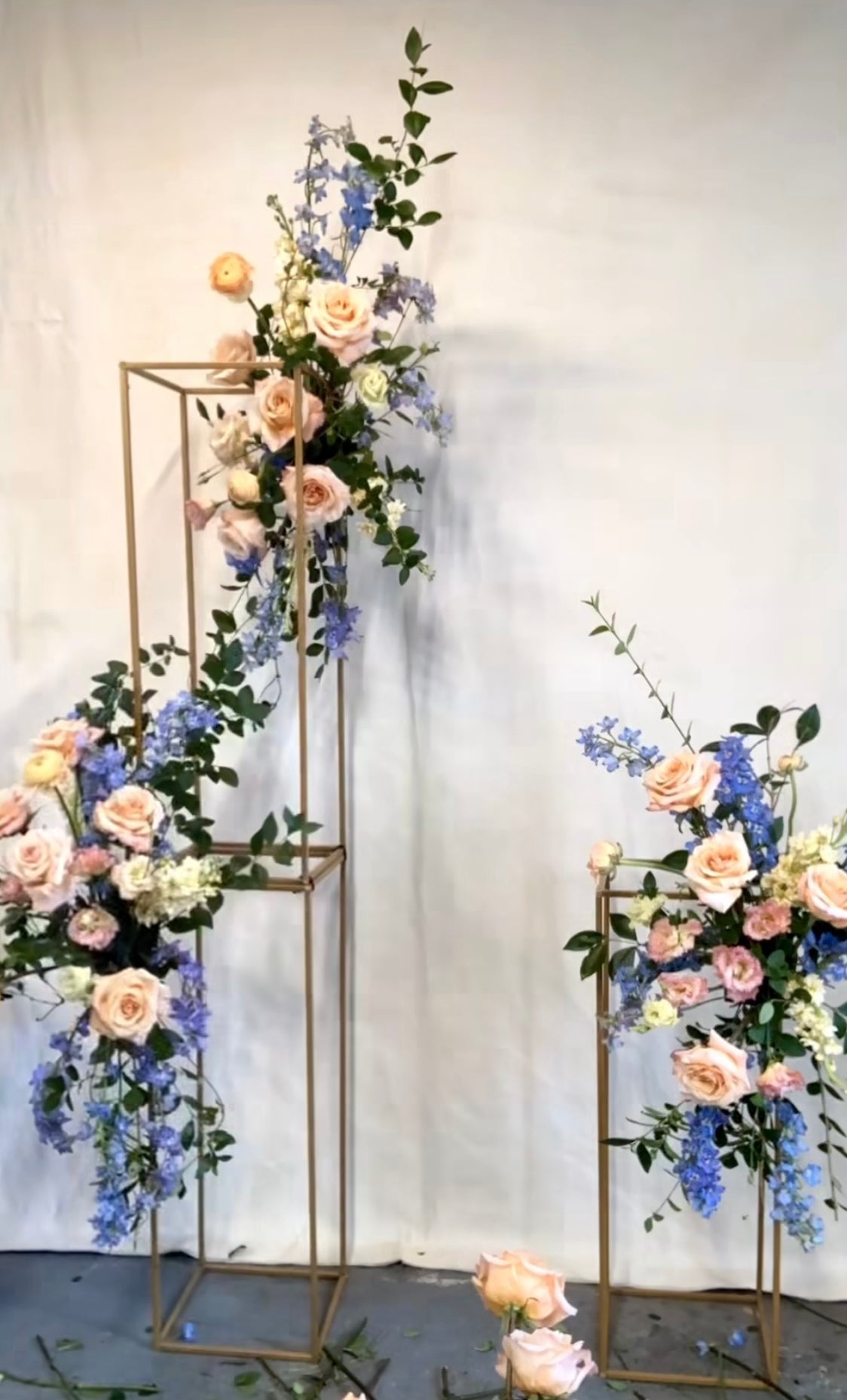 Customizable silk florals on elegant gold stands for event decoration.