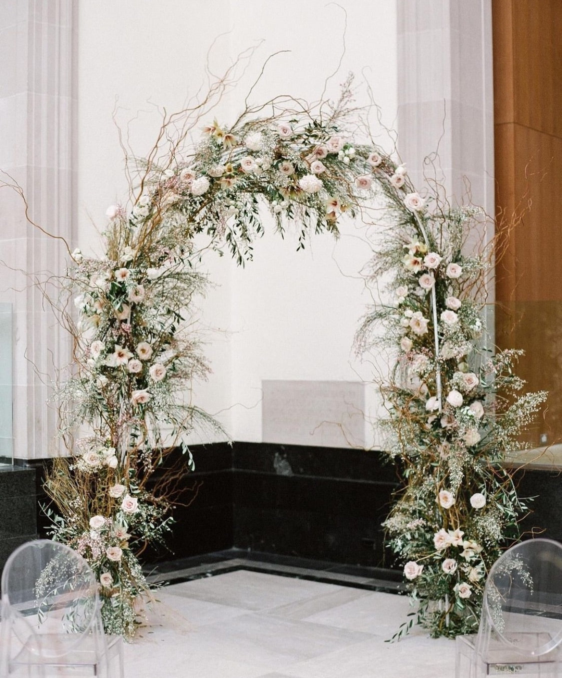 Elegant white metal arch used as a backdrop for an outdoor garden event.