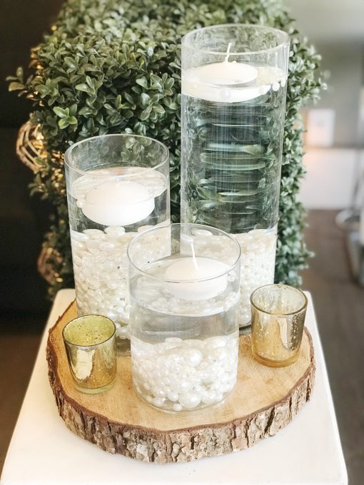 Floating candles in glass vases with decorative rocks at a wedding