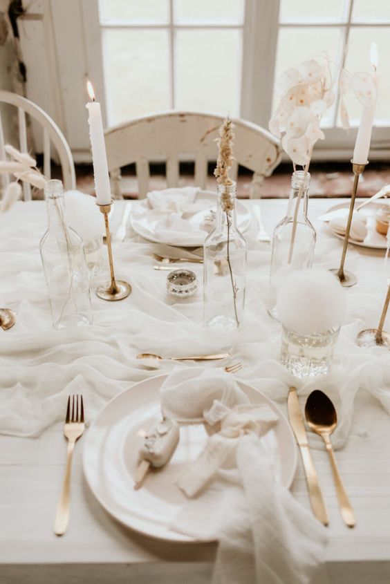 Close-up of gold candle stick holders with white candles on a beautifully decorated table.