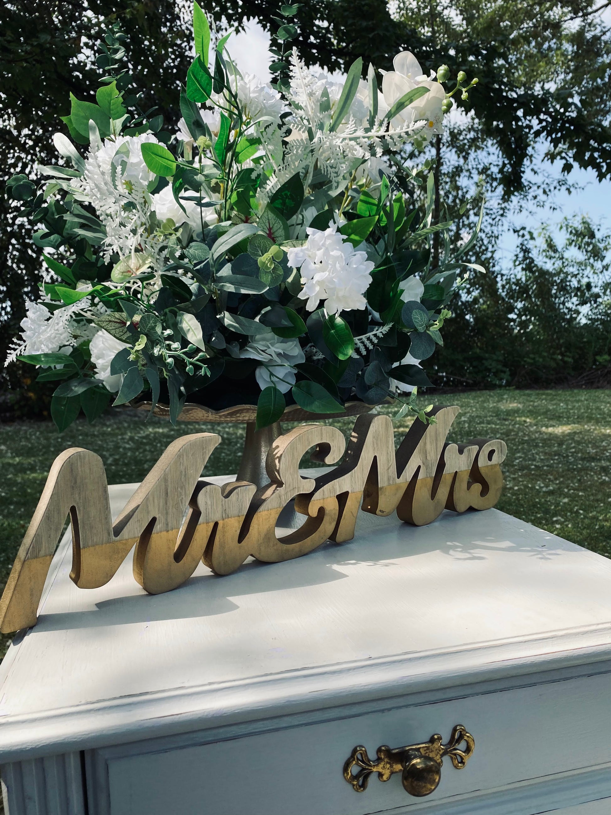 Elegant large silk faux topiary arrangement on display at an outdoor wedding.