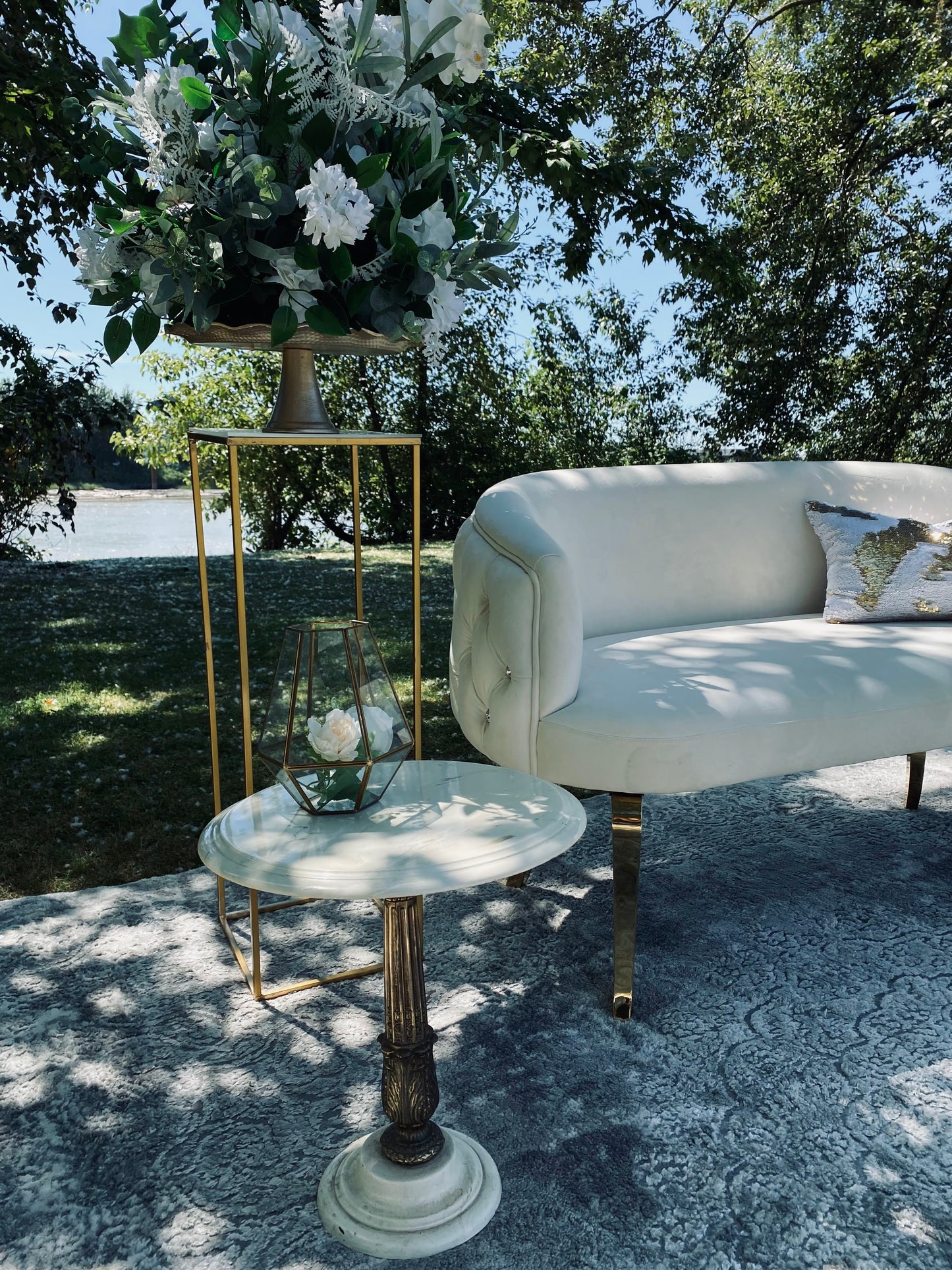 Antique Marble and Gold Side Table set up outdoors next to a white sofa.