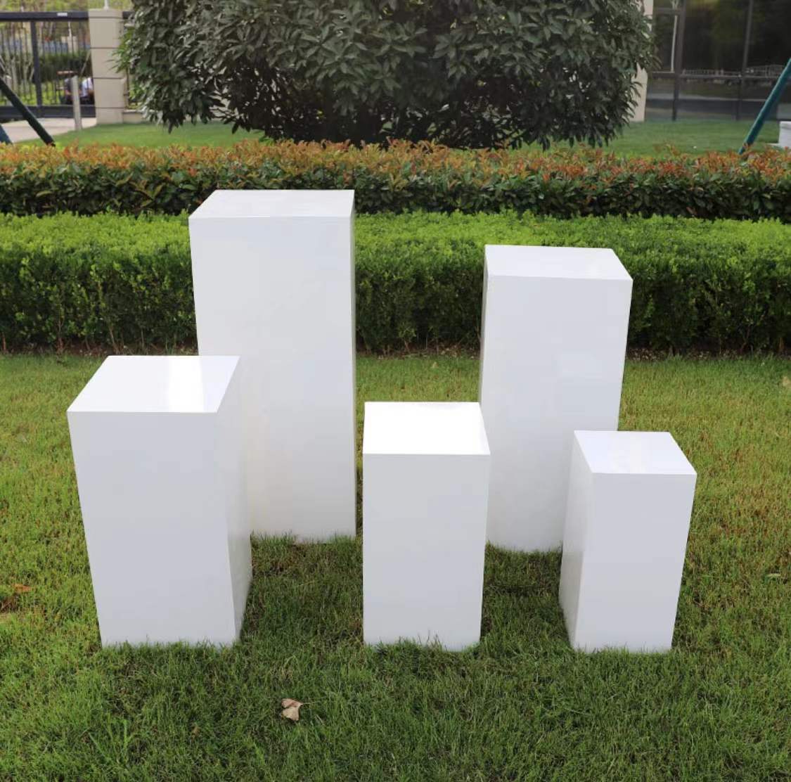 White metal square stands used for floral arrangements in an outdoor setting.