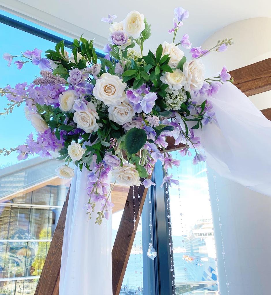 Silk Arch Floral Arrangement with white and purple flowers on a wooden arch.