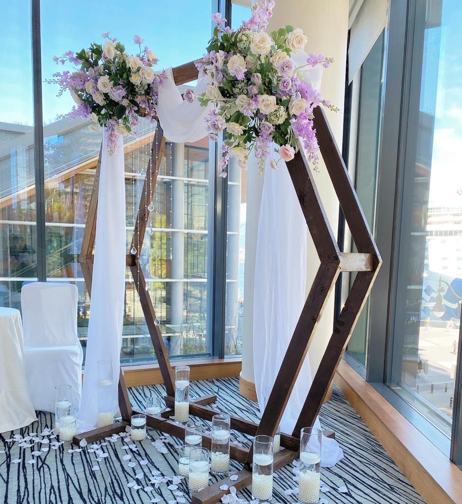 Silk Arch Floral Arrangement with white and purple flowers on a wooden arch.