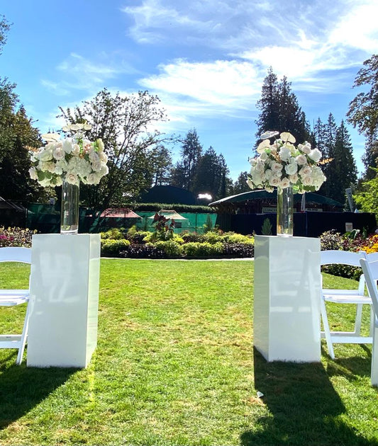 White metal square stands used for floral arrangements in an outdoor setting.