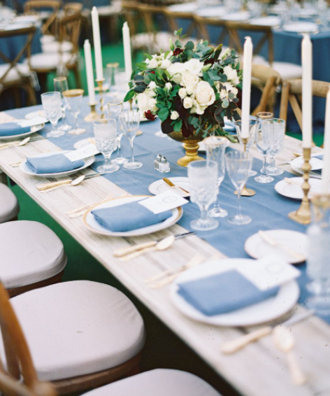 Elegant table setting with gold candle stick holders and white candles at a wedding reception.