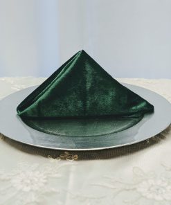 Luxurious emerald green velvet napkin on a silver charger plate.Luxurious emerald green velvet napkin on a silver charger plate.