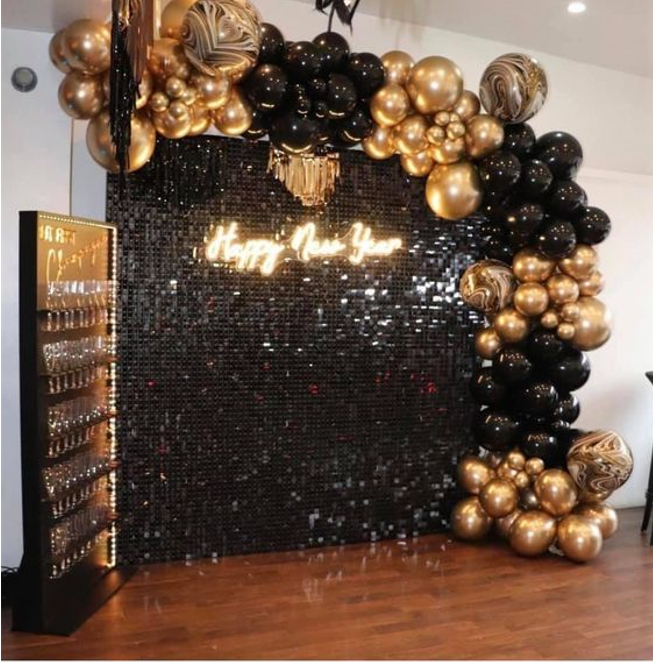 Black and gold balloon display with teddy bear and marquee letters.