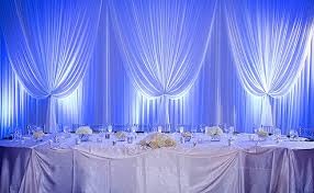 White draping backdrop with greenery for a garden-themed wedding.